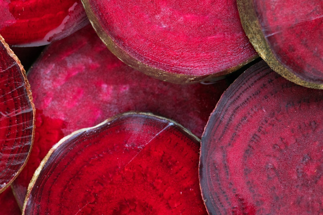 Cross-sections of dark red beetroot slices stacked together, showing natural ring patterns.