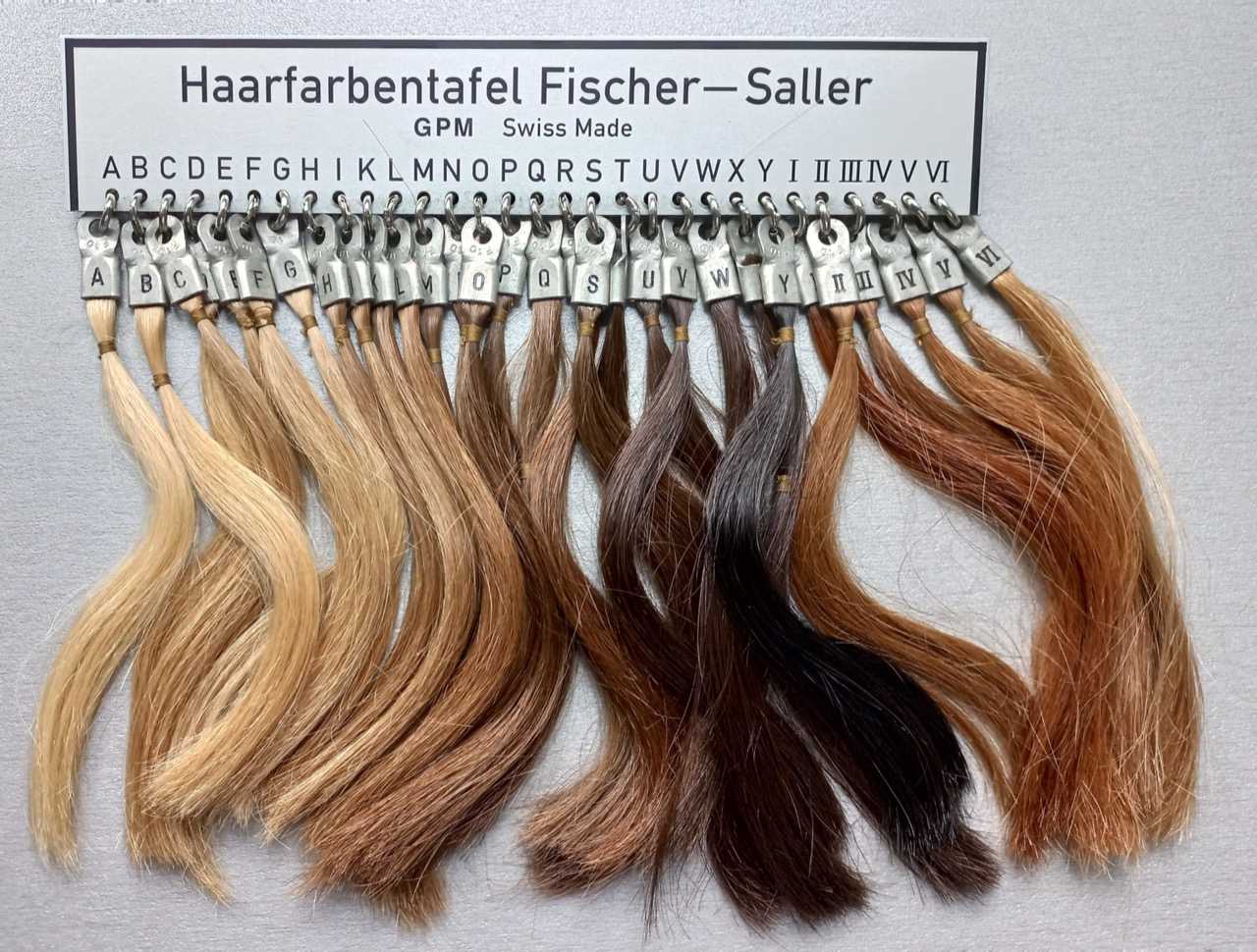 A Fischer-Saller reference scale of numbered real hair-sample swatches, ranging from pale blonde through brown to near-black.