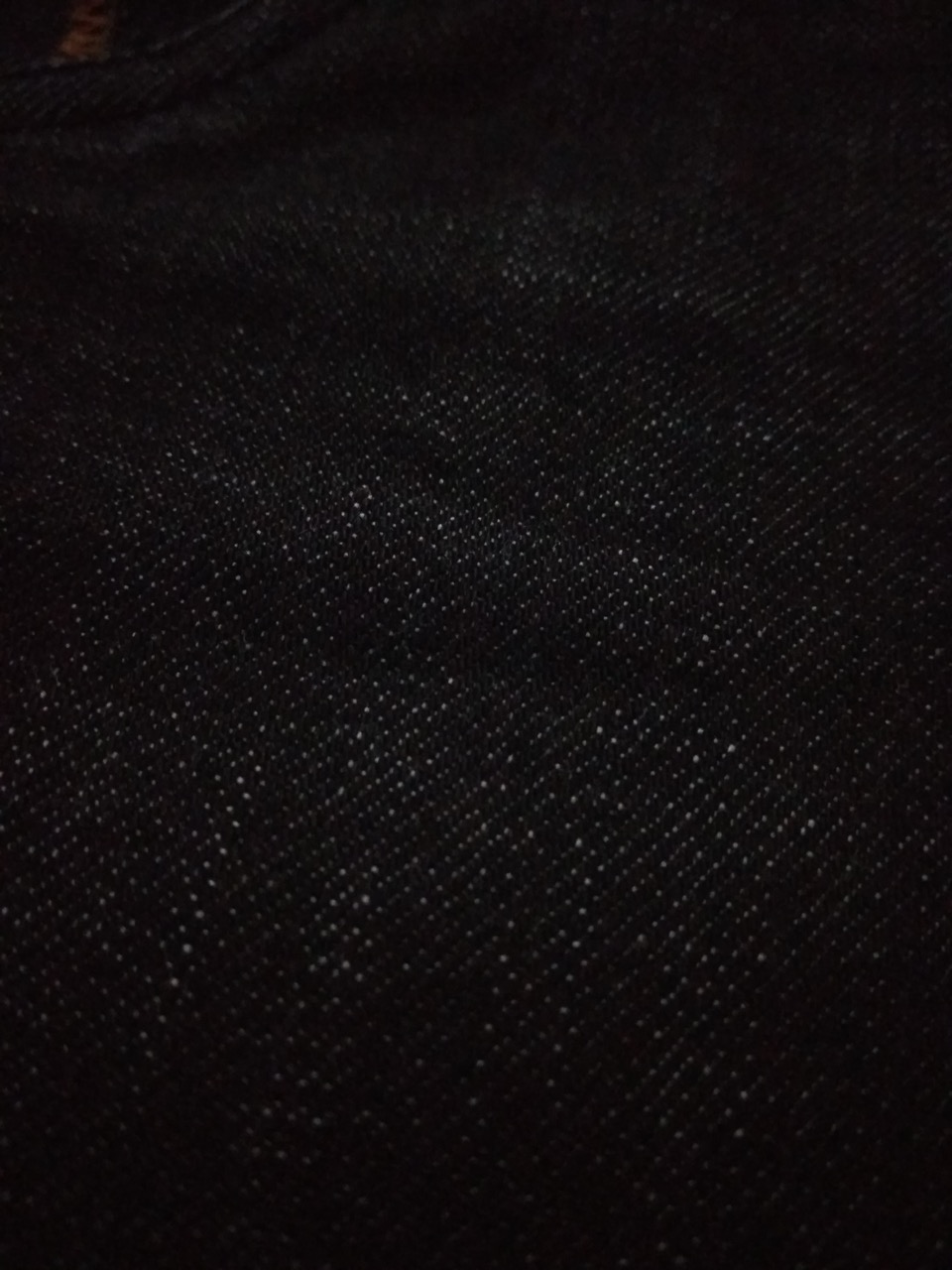 Close-up of dark, near-black denim fabric showing its fine diagonal twill weave.