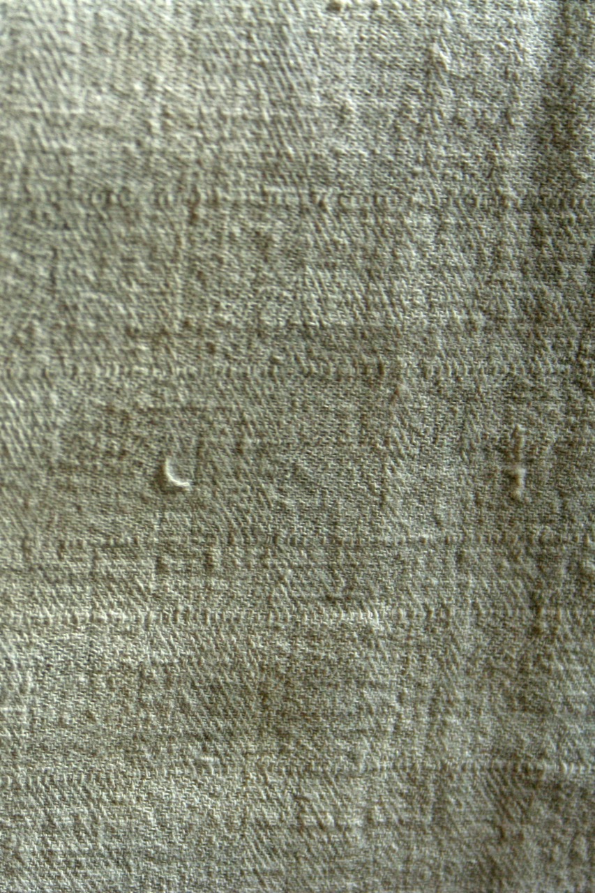 Close-up of an antique hand-woven linen textile, showing its natural fibre texture.