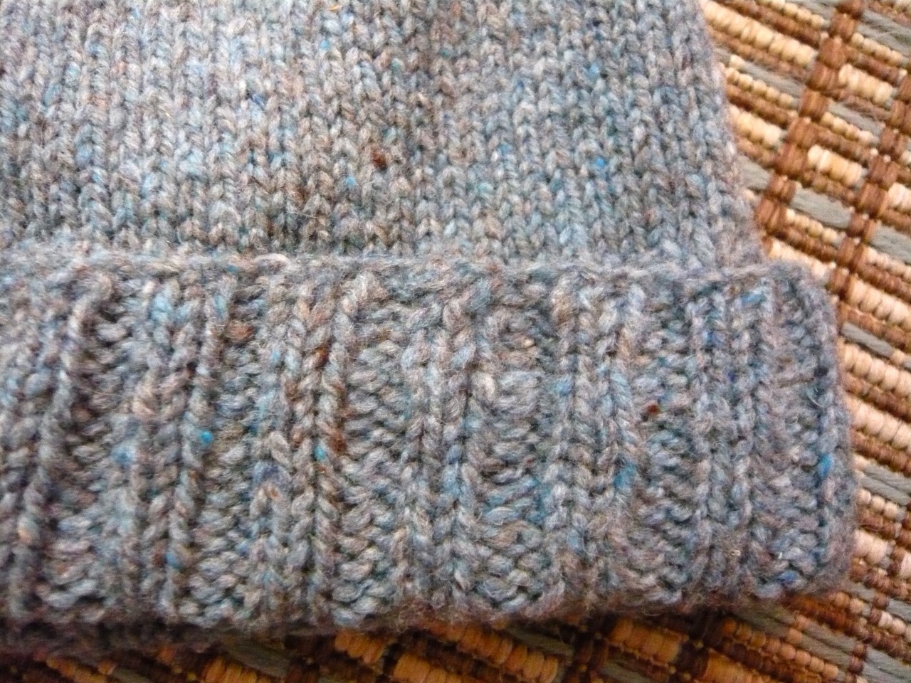 Close-up of ribbed hand-knitted wool in a heathered grey-brown yarn.