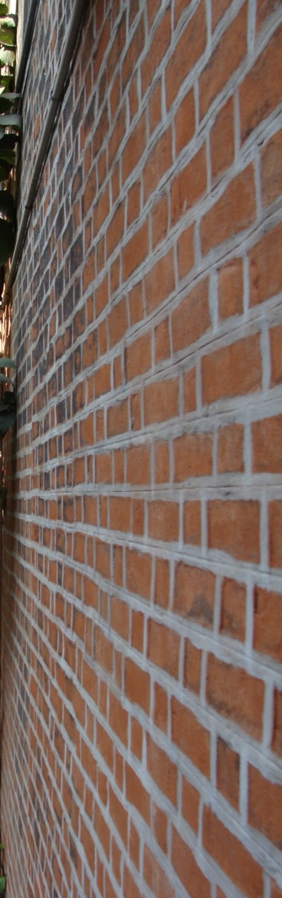 Close-up of a red brick wall with painted mortar joints, viewed at an angle.