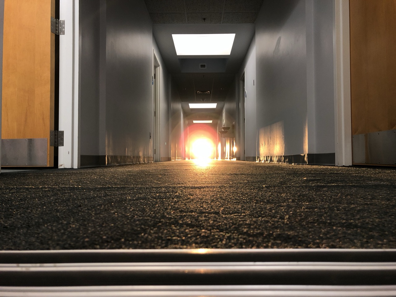 A long corridor with a strong warm light source at the far end, fading to shadow near the camera.