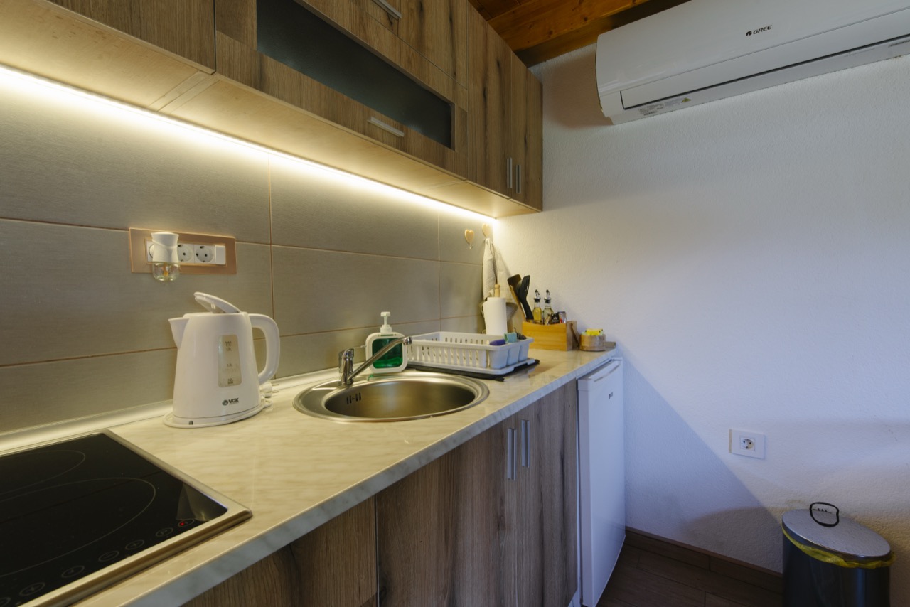 A modern kitchen with wooden cabinets, warm under-cabinet lighting, and a pale worktop.