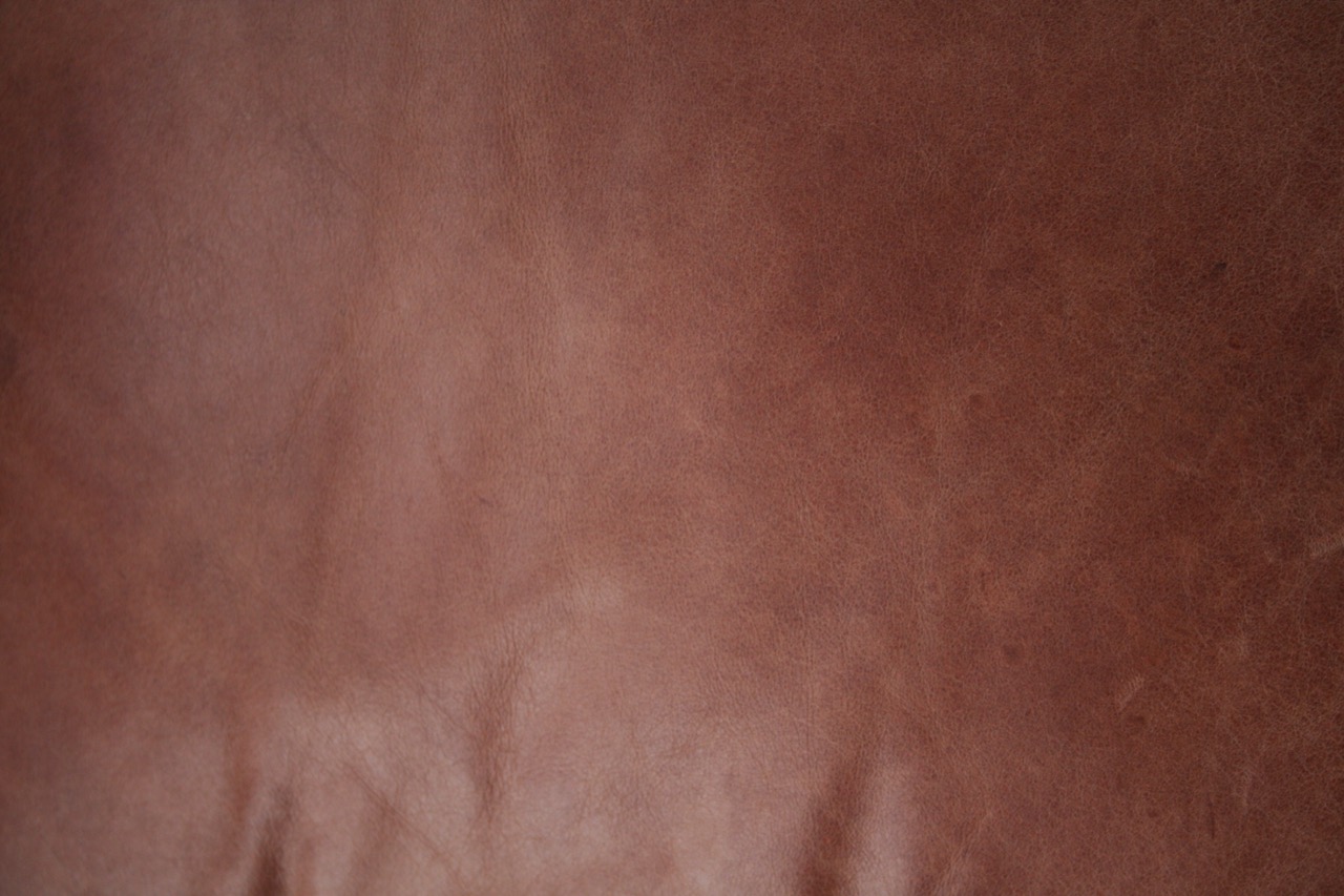 Close-up of warm reddish-brown grained leather with natural creases.