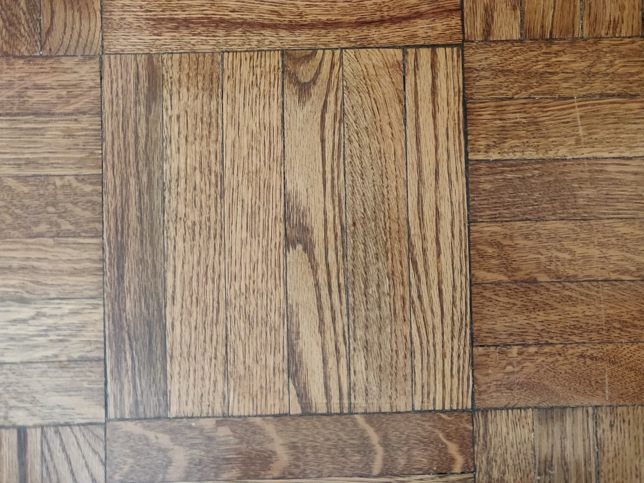 Close-up of oak parquet flooring showing linear wood grain and colour variation between strips.